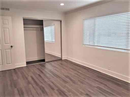 modern bedroom with mirrored closet and wood style floors
