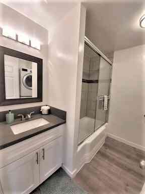 white shaker vanity and glass tub enclosure